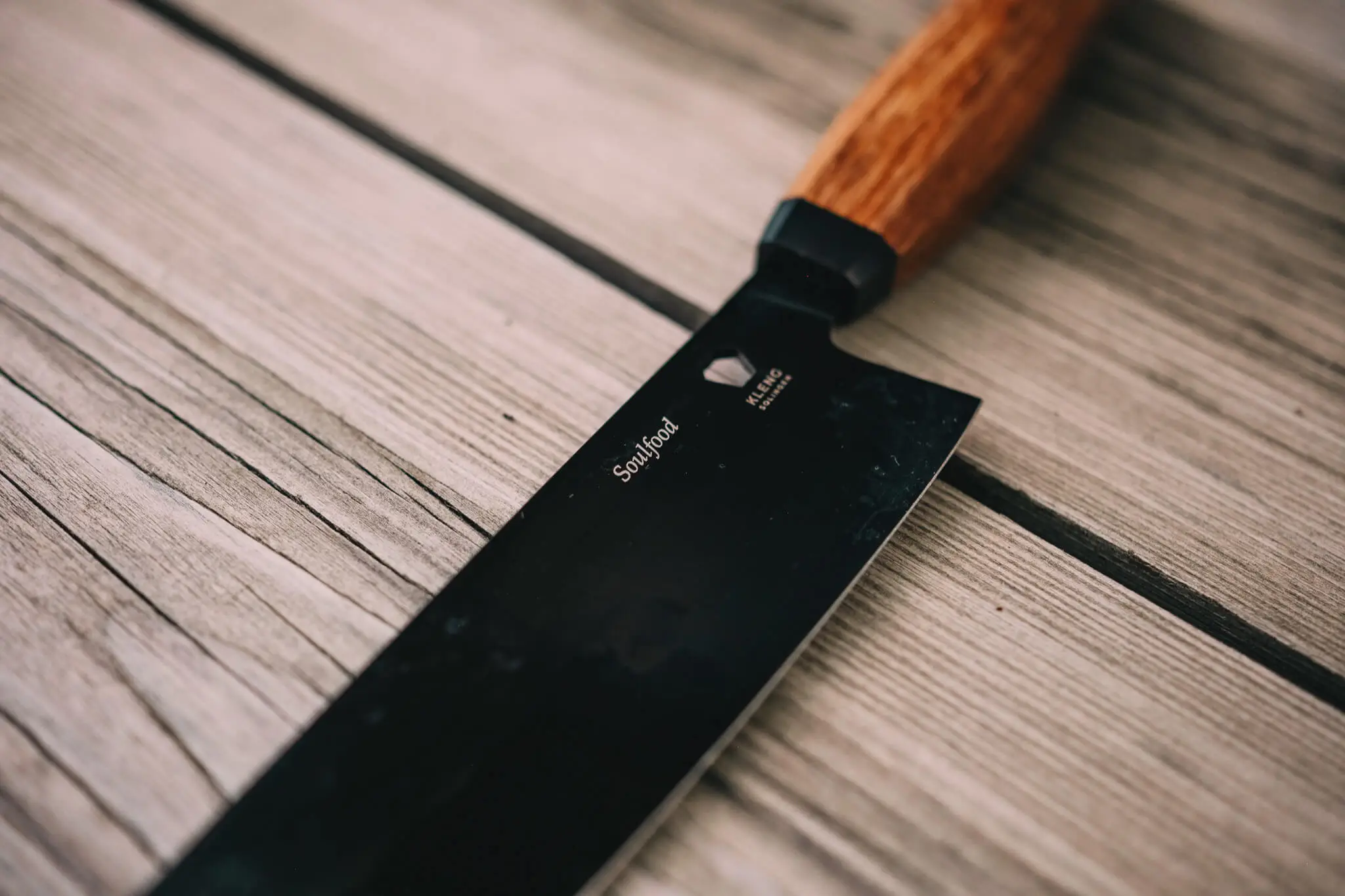 Kitchen knife with a wooden handle on weathered wooden boards